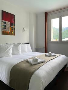 1 dormitorio con 1 cama grande y toallas. en HOTEL & SPA GASQUET en Luchon