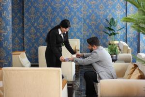 Una donna sta aiutando un uomo in una stanza di Safir Hotels Çorlu a Corlu