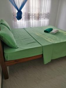 1 cama con sábanas y almohadas verdes frente a una ventana en White House, en Weligama