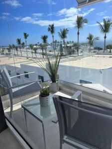 a balcony with two chairs and a table and palm trees at Beach Paradise in Tías