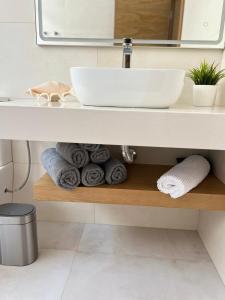 ein Badezimmer mit Waschbecken und einem Stapel Handtücher in der Unterkunft Beach Paradise in Tías