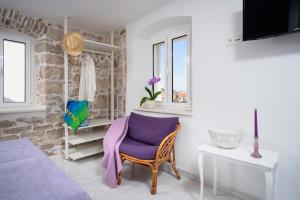 a room with a purple chair and a table and window at Apartments Lotti 2 in Stari Grad