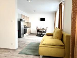 a living room with a yellow couch and a kitchen at Sky Apartments 512 in Pilsen