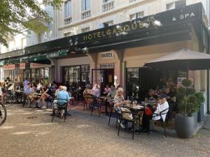 eine Gruppe von Personen, die vor einem Restaurant an Tischen sitzen in der Unterkunft HOTEL & SPA GASQUET in Luchon