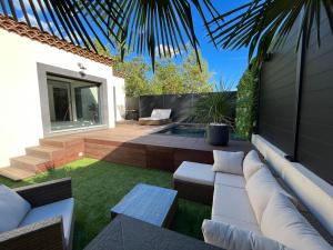 un patio con muebles blancos y césped verde en Le Vertu’Ose en Rougiers