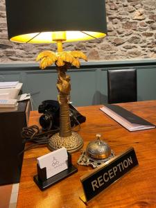 eine Lampe auf einem Tisch mit einem Schild, auf dem der Empfang steht. in der Unterkunft HOTEL & SPA GASQUET in Luchon