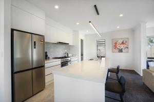 a white kitchen with a refrigerator and a counter at Experience The Magic of Riverside Living - 5 beds in Hamilton