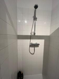 a shower with a shower head in a white tiled bathroom at 5ensational appartement - Centre in Brussels