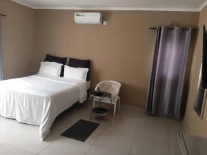 Kitwe的住宿－GOLDLAND APARTMENTS，卧室配有白色的床和椅子