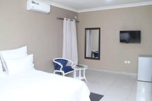 a bedroom with a bed and a tv and a chair at GOLDLAND APARTMENTS in Kitwe
