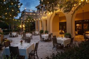 un restaurante con mesas blancas, sillas y luces en The Alfond Inn en Orlando