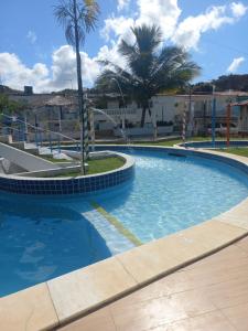 a large swimming pool with palm trees and buildings at Flat Beach Itamaracá - pousada FBI in Itamaracá