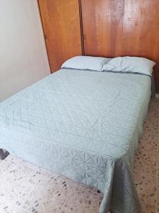 a bed with a blue comforter in a room at Malecón Casa Grande Económica Gran Ubicación in Mazatlán