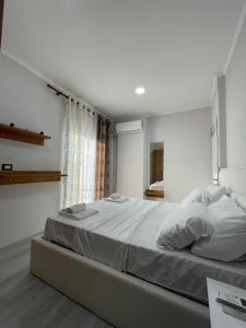 een slaapkamer met een groot bed met witte lakens bij Stone City Apartament in Gjirokastër