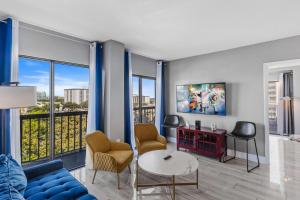 a living room with a blue couch and chairs and windows at 6165 Carrier Drive 3805 in Orlando