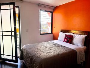 una camera da letto con un letto con una parete arancione di Hotel MH a Chignahuapan