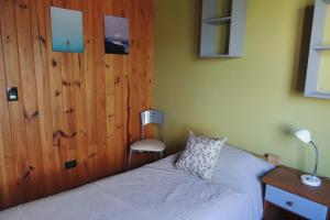 1 dormitorio con 1 cama y pared de madera en Allegra, casa de descanso en San Martín de los Andes