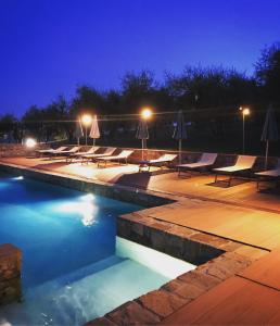 uma piscina à noite com cadeiras e guarda-sóis em Locanda La Casina Di Lilliano em Castellina in Chianti