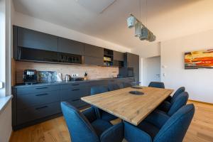a kitchen with a wooden table and blue chairs at TAMLiving Center Luxury 4 rooms Smart TV Kitchen Great View in Graz