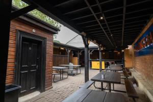 een patio met houten tafels en banken en een gebouw bij The Hyde - At Dunning's Bar in Watford