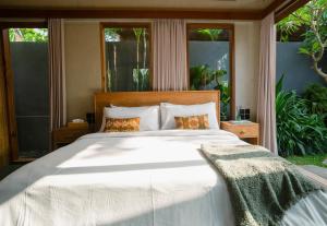 um quarto com uma grande cama branca e janelas em The Surf Shack - Stylish New 1 BR Studio w/ plunge pool em Uluwatu