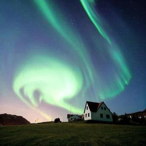 una imagen de las luces del norte en el cielo sobre una casa en Minna-Mosfell Guesthouse, en Mosfellsbær