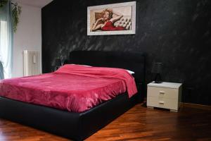 un letto nero con piumone rosso in una camera da letto di Zephyr B&B apartment a Novi Ligure