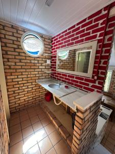 a bathroom with a sink and a red brick wall at Villa Cabanas - Pé na areia in Governador Celso Ramos