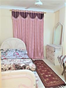 a bedroom with a bed and a pink curtain at Furnished apartment in Minya in Al Minya