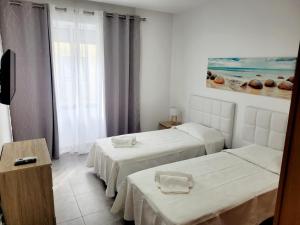 a hotel room with two beds and a window at Penedo Grande suítes T2 in São Bartolomeu de Messines