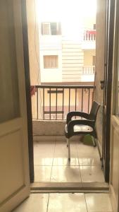 Zimmer mit einem Balkon mit einem Stuhl und einem Fenster in der Unterkunft Furnished apartment in Minya in al-Minya