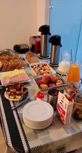 a table topped with plates and pastries and orange juice at Hostel Kaizen in Curitiba