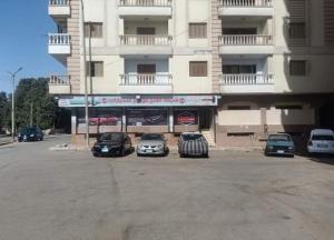 Furnished apartment in Minya في المنيا: موقف للسيارات مع وقوف السيارات أمام المبنى