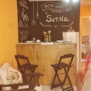 um bar com duas cadeiras e um micro-ondas em Casa Maria Flor em Arraial do Cabo