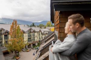 Ein Mann steht auf einem Balkon mit Blick auf eine Stadt in der Unterkunft Executive Inn Whistler in Whistler