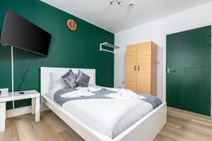 een slaapkamer met een bed met een groene muur bij City Gate Guest House in Londen