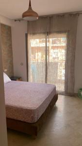 a bedroom with a bed and two large windows at Appartement propre et calme in Casablanca