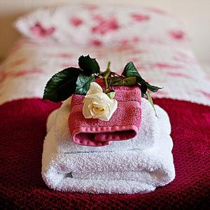 una pila de toallas con una rosa blanca en la parte superior en Minna-Mosfell Guesthouse en Mosfellsbær