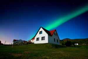 una casa con las verdes luces del norte en el cielo en Minna-Mosfell Guesthouse, en Mosfellsbær