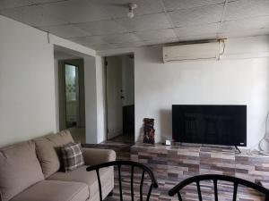 a living room with a couch and a tv at Mango Vert Apartment in Arima