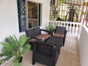 a porch with two wicker chairs and a table at Mango Vert Apartment in Arima