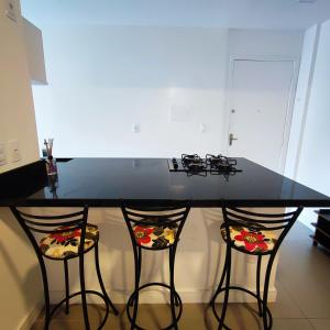 a kitchen with a black counter with two bar stools at Apartamento Pertinho da Praia, faça tudo a pé! in Balneário Camboriú +4 photos