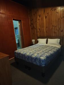a bedroom with a bed with a wooden wall at Hostal Capricho de Carlitos in Valdivia