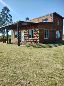 una casa en un campo de hierba delante de una casa en La pacaa` en Bella Vista