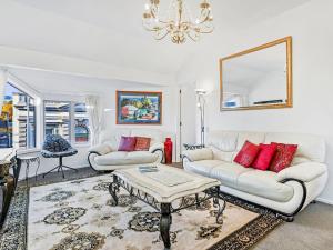 a living room with white furniture and a chandelier at Akaroa Village Inn in Akaroa