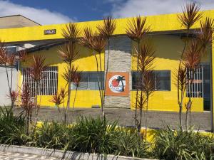 ein gelbes Gebäude mit Palmen davor in der Unterkunft Pousada Beira-mar I in Bertioga