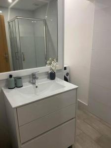 ein weißes Badezimmer mit einem Waschbecken und einem Spiegel in der Unterkunft DayDream Apartament in Viana do Castelo