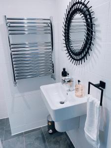 Baño blanco con lavabo y espejo en Two Bedroom Urban Retreat in the Heart of Exeter en Exeter