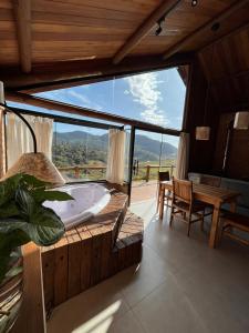 a tub in a room with a large window at Pousada Ho'oponopono Chalets & Wine in Sapucaí-Mirim