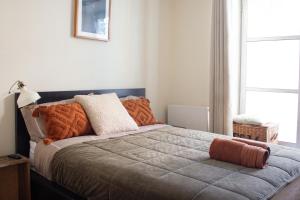 a bedroom with a large bed with orange pillows at Cozy bedroom in Clapton home in London